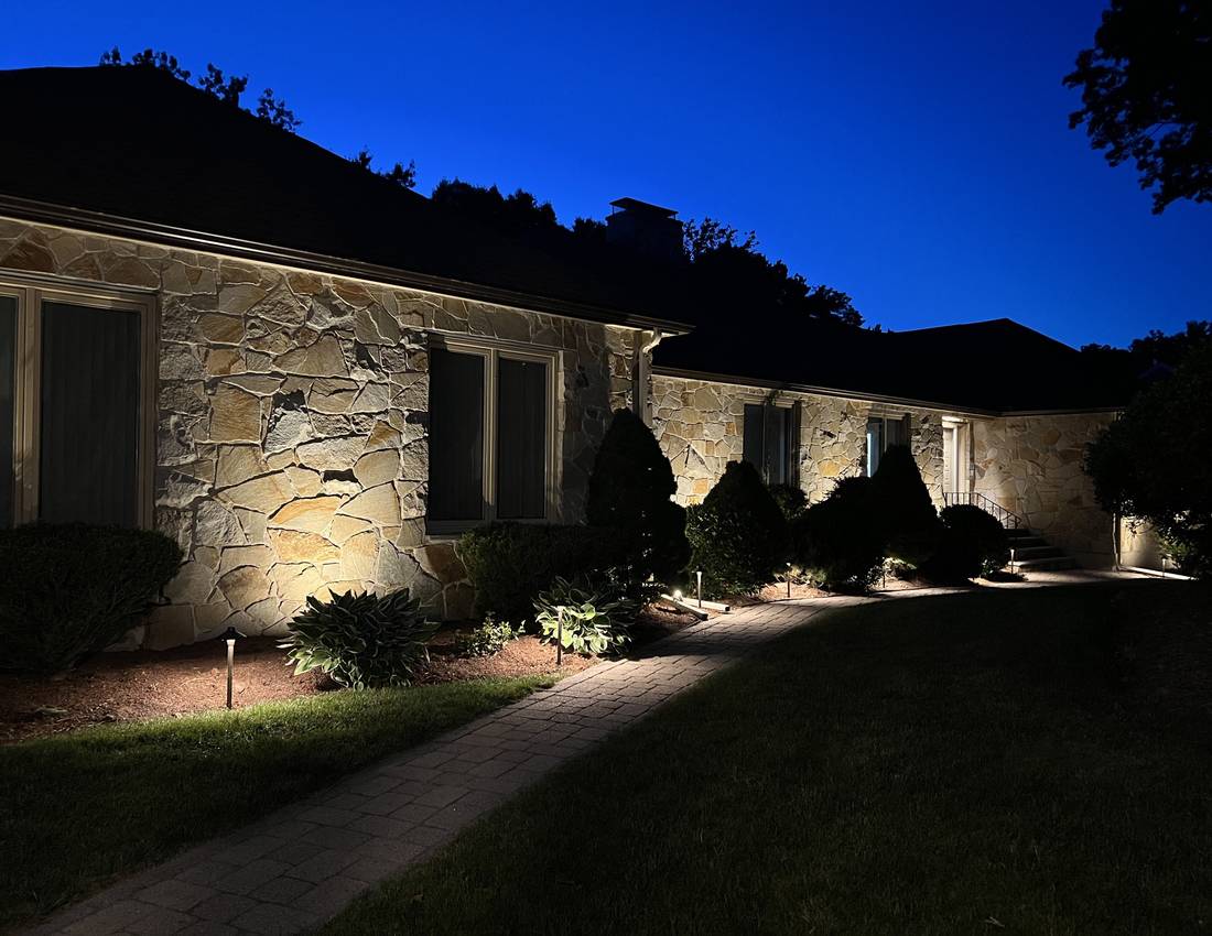 Canton stone home with warm walkway and shrub uplighting