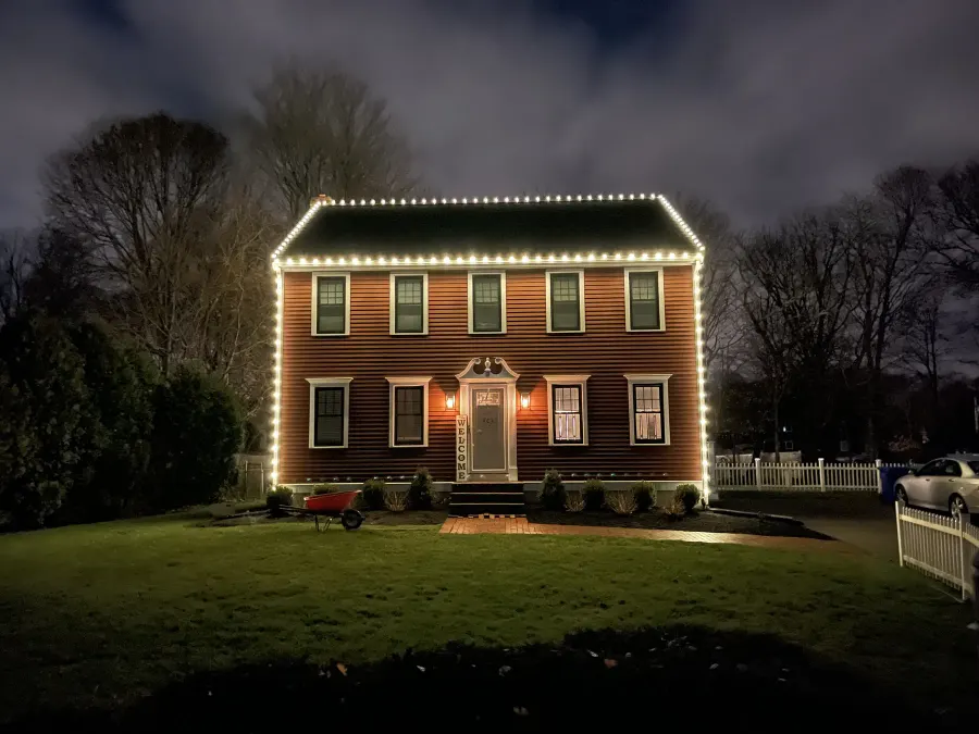Warm white holiday roofline on a brick colonial