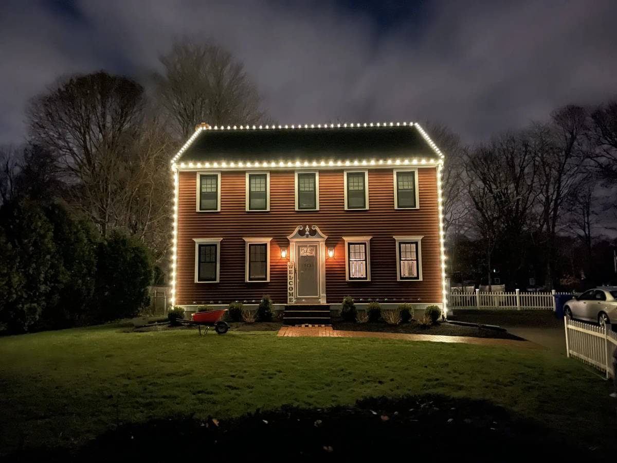 Warm white holiday roofline on a brick colonial