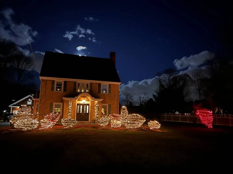 Holiday lights on front shrubs and a colonial entry