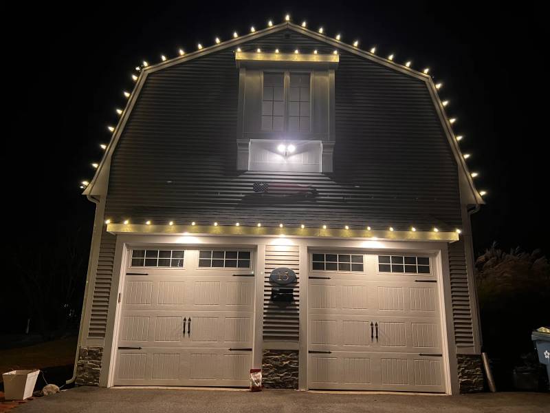 White holiday lights tracing a gambrel garage roof
