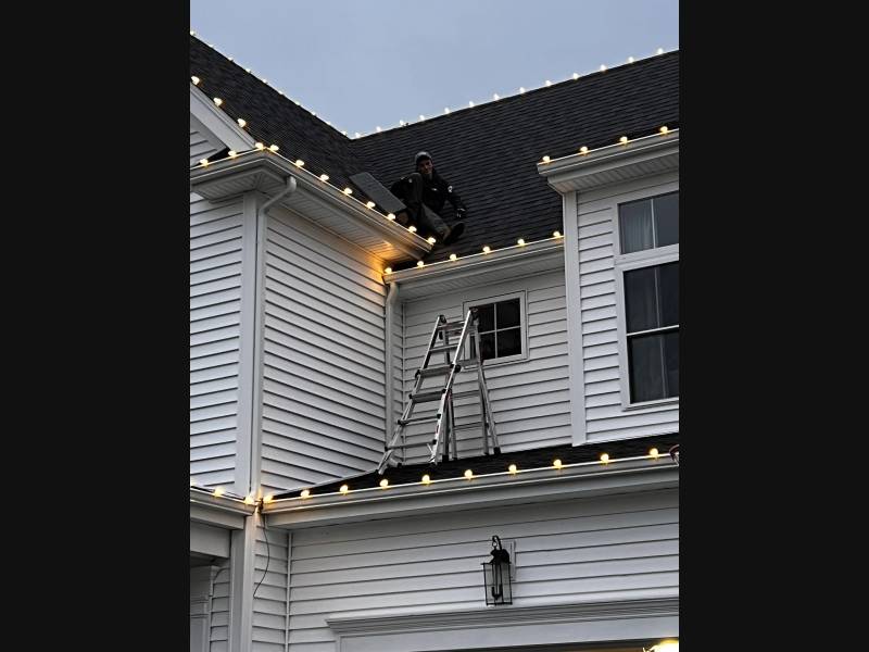 Holiday bulbs clipped along white gutters during installation