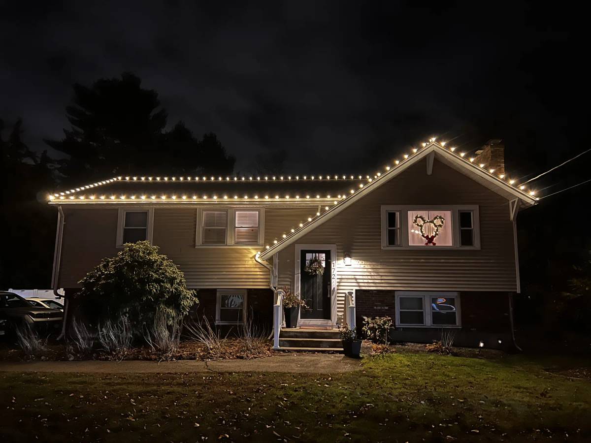 Warm white holiday roofline lights on a split-level home