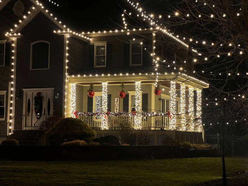 Victorian home with holiday roofline lights and illuminated porch columns