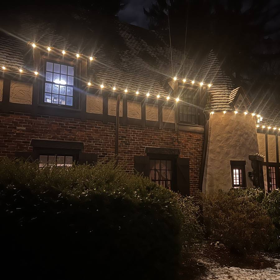 Warm white roofline lights across a Tudor-style Newton home
