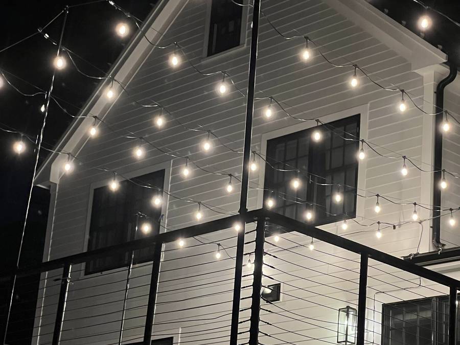Close view of warm cafe lights illuminating a backyard deck
