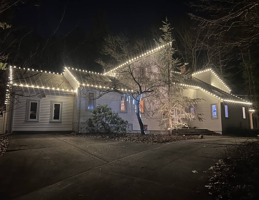 Warm white holiday roofline lighting on a Sharon home