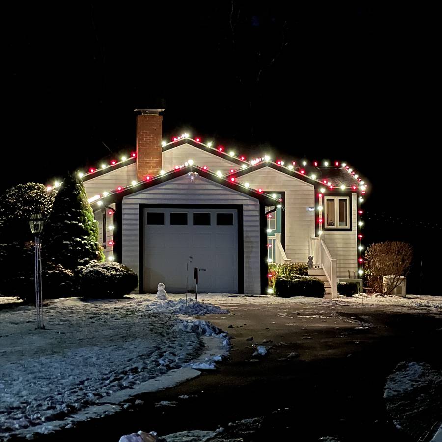 Red and white holiday roofline lighting on a Sharon garage and entry